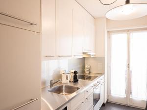 a kitchen with white cabinets and a sink at Apartment Chesa Romantica 17 by Interhome in St. Moritz