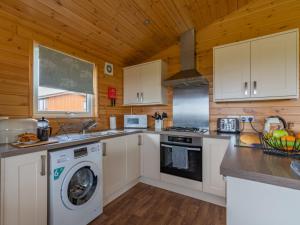 a kitchen with white cabinets and a washer and dryer at Chalet Loch Leven Lodge 6 by Interhome in Kinross