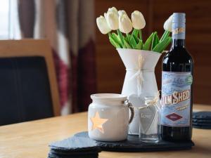 a bottle of wine sitting next to a vase of flowers at Chalet Loch Leven Lodge 12 by Interhome in Kinross