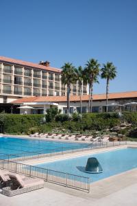 un grand hôtel avec une piscine et des palmiers dans l'établissement Dan Accadia Herzliya Hotel, à Herzliya