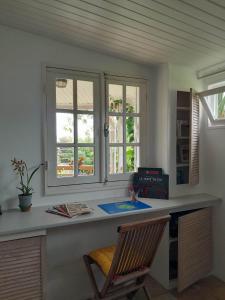 a desk in a room with two windows and a chair at Chalet PLEINSUD in Le Tampon