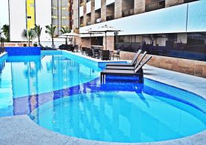 een zwembad met een bank in het midden van een gebouw bij GoldFlat in João Pessoa