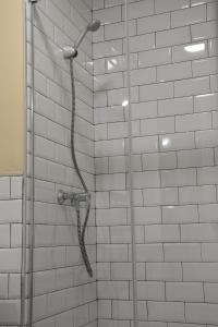 a shower in a bathroom with white tiles at Alegoría Coliving Experience Residencia in Seville