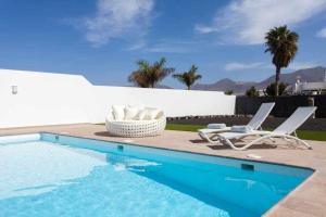 una piscina con 2 tumbonas junto a una casa en Homu Bianca Fantástica villa con piscina privada, en Playa Blanca