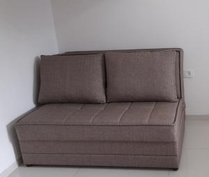 un sofá marrón sentado en una esquina de una habitación en Regina's place, en Or ‘Aqīvāh
