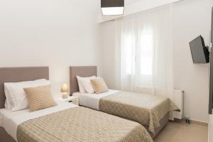 Habitación blanca con 2 camas y TV. en Al Santo Apartments en Zakynthos