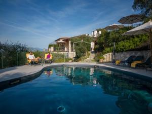 ein Paar sitzt in Stühlen neben einem Pool in der Unterkunft Residence Ca Del Lago in Torri del Benaco