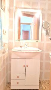 ein Badezimmer mit einem weißen Waschbecken und einem Spiegel in der Unterkunft 3 bedrooms appartement at Tavernes de la Valldigna 50 m away from the beach with sea view furnished terrace and wifi in El Brosquil