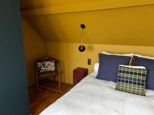 um quarto com uma cama com almofadas azuis e uma cadeira em Le gite. em Paluel