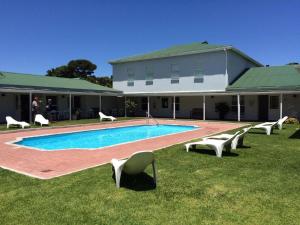 a house with a swimming pool and chairs in the grass at River Club 4213 in Plettenberg Bay