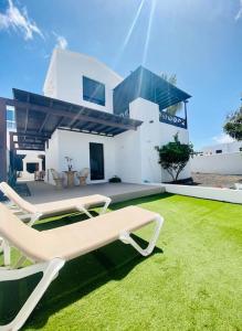 ein Haus mit einem grünen Hof mit einer Bank in der Unterkunft Villa muy cerca de la Playa. in Tías