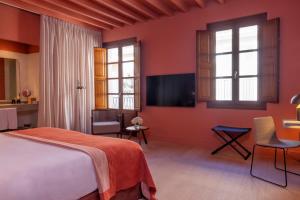 a bedroom with a bed and a tv and windows at Hotel Calatrava in Palma de Mallorca