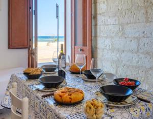 un tavolo con piatti di bicchieri da cibo e da vino di Sea Breeze Sea View Seafront a San Foca
