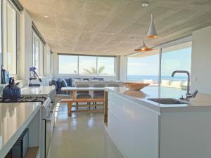 a kitchen with white cabinets and a living room with the ocean at Betty in Plettenberg Bay