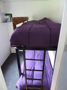 a bunk bed with purple sheets on top of it at mobil home dans camping 3 etoiles mas de lastourg avec piscine,snack, in Villefranche-de-Conflent