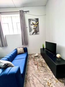 sala de estar con sofá azul y TV en Cosy Apartment next to Maboneng, en Johannesburgo
