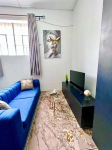sala de estar con sofá azul y mesa en Cosy Apartment next to Maboneng, en Johannesburgo