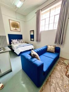 sala de estar con sofá azul y cama en Cosy Apartment next to Maboneng, en Johannesburgo