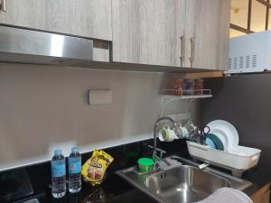 uma cozinha com lavatório e garrafas de água no balcão em Cozy condo at Pasay near MOA Arena em Manila