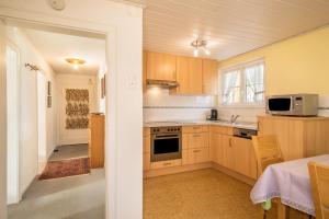 eine Küche mit Holzschränken, einer Spüle und einer Mikrowelle in der Unterkunft Haus Kees - Wohnung 1 in Kressbronn am Bodensee