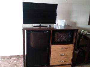 TV en la parte superior de un soporte de madera con nevera en German Village Inn Motel, en Columbus