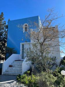 una casa azul y blanca con escaleras y un árbol en Beachfront Studio Socrates en Gennadi