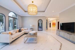 een woonkamer met een bank en een tv bij Maison Privee - Private Pool & Beach Access Villa with Cinematic Vws in Dubai