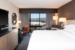 Sheraton Mission Valley San Diego Hotel في سان دييغو: غرفة فندقية بسرير كبير ونافذة كبيرة