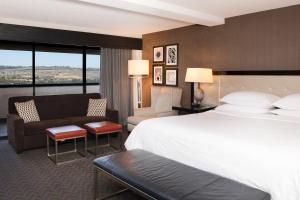 Sheraton Mission Valley San Diego Hotel في سان دييغو: غرفة فندقية بسرير كبير واريكة
