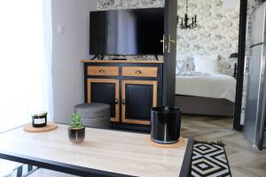 a room with a table with a tv and a bedroom at L'antichambre, neuf avec jardin à 100m de la mer in Donville-les-Bains