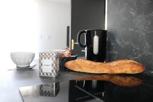 a bagel on a counter with a coffee mug and a cup at L'antichambre, neuf avec jardin à 100m de la mer in Donville-les-Bains +11 photos