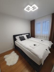 um quarto com uma cama grande com lençóis brancos e uma janela em Jahorina Forest View em Jahorina