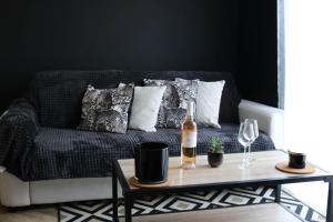 a couch with pillows and a bottle of wine on a table at L'antichambre, neuf avec jardin à 100m de la mer in Donville-les-Bains