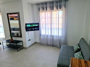 a living room with a couch and a tv at APARTAMENTOS ELEMAR free luggage storage in Málaga