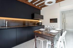 a kitchen with a wooden table with white chairs at Dimora San Lorenzo Luxury Apartment in Venice
