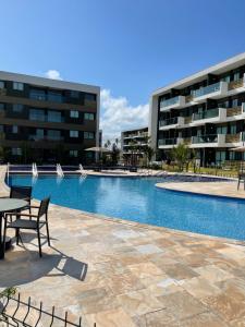 a swimming pool with a table and chairs in front of a building at Mana Beach Experience - Muro Alto - Flat Luxo 2 qtos in Porto De Galinhas