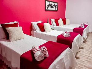 a room with four beds with red and white sheets at Pousada Primavera in São Miguel do Gostoso