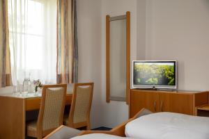 een hotelkamer met een televisie en een tafel en stoelen bij Pension Demmel in Bruckmühl