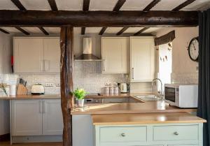 a kitchen with white cabinets and a clock on the wall at Garth Cottage, Castle Carrock, Nr Carlisle in Castle Carrock