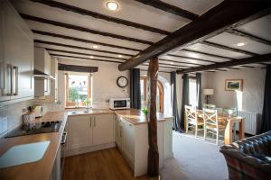 a kitchen with white cabinets and wooden ceilings and a living room at Garth Cottage, Castle Carrock, Nr Carlisle in Castle Carrock