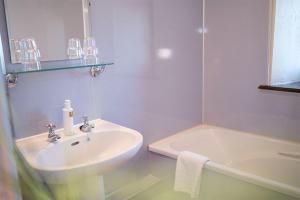a white bathroom with a sink and a bath tub at Garth Cottage, Castle Carrock, Nr Carlisle in Castle Carrock