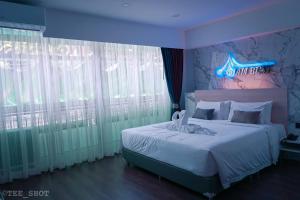 a bedroom with a bed with a neon sign on it at Siam Best Inn in Makkasan