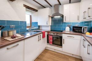 a kitchen with white cabinets and blue tiles at Gill Cottage, Castle Carrock, Nr Carlisle in Castle Carrock