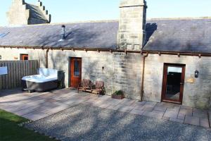 a stone house with a bath tub on a patio at Oak Cottage, Castle Carrock, Nr Carlisle in Castle Carrock