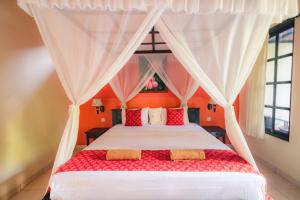 - une chambre avec un lit doté d'oreillers rouges et blancs dans l'établissement Giri Sari Guest House Pemuteran Bali, à Pemuteran