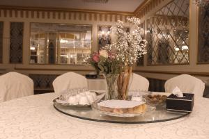 a table with a cake and a vase of flowers at Velvet Hotel Jeddah in Jeddah