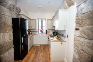 a kitchen with white cabinets and a black refrigerator at Tower Barn Cottage, Castle Carrock, Nr Carlisle in Castle Carrock