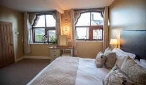 a bedroom with a large bed with two windows at Tower Barn Cottage, Castle Carrock, Nr Carlisle in Castle Carrock