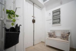 un corridoio bianco con panchina e pianta di Wi-Fi & NETFLIX - Luxe Suite nel Cuore di Salerno a Salerno