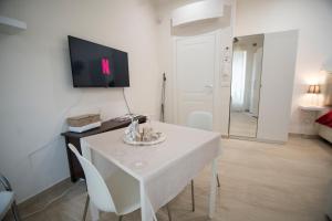 ein Wohnzimmer mit einem weißen Tisch und einem TV in der Unterkunft Wi-Fi & NETFLIX - Luxe Suite nel Cuore di Salerno in Salerno